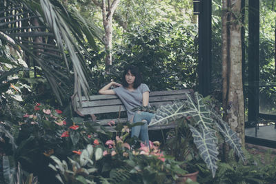 Young woman sitting by plants in forest