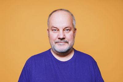 Portrait of man standing against yellow background