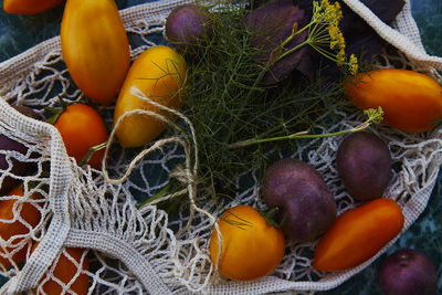 Summer vegetables in eco shopping bag with herbs and  tomatoes, purple potatoes