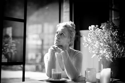 Portrait of woman sitting by window at restaurant