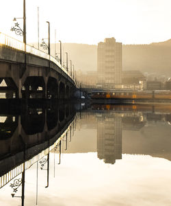 Bridge over river against sky in city