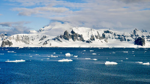 Scenic view of sea and snowcapped mountains against sky