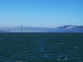 View of suspension bridge over sea against clear sky