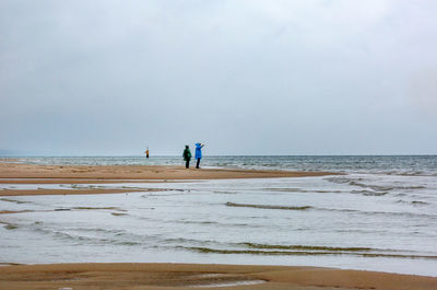 People standing at beach against sky