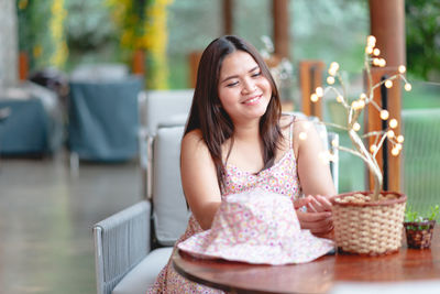 Portrait of a smiling young woman sitting on table