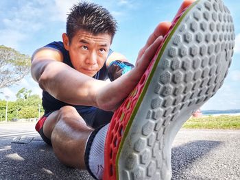 Man exercising on road against sky