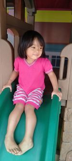 Cute girl sitting on slide at playground