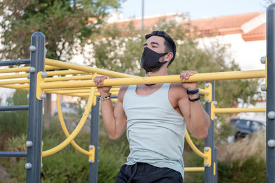 Young man wearing mask exercising at playground
