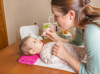 Portrait of cute girl holding baby while standing on floor