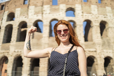 Portrait of smiling mid adult woman against building