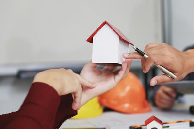 Close-up of man holding paper with hand on table