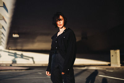 Portrait of young woman standing against car