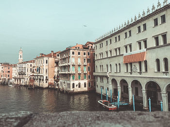 Buildings by canal against sky in city