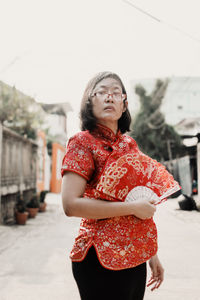 Woman holding hand fan standing in city