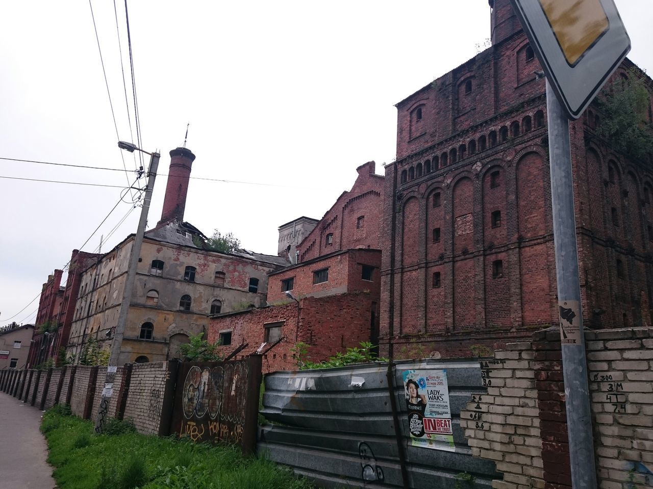 building exterior, architecture, built structure, clear sky, low angle view, transportation, building, sky, city, day, street, outdoors, street light, brick wall, railing, railroad track, no people, construction site, communication, residential structure