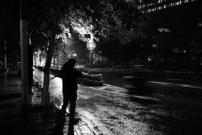 Rear view of silhouette man walking on street at night