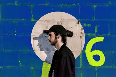 Young man standing by blue wall