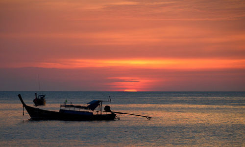 Boat in sea against sky during sunset