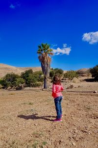 Boy standing on field against clear blue sky