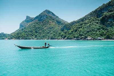 Man sailing on boat by tree mountains in ko samui