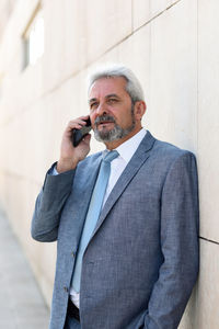 Mature man using mobile phone while standing outdoors