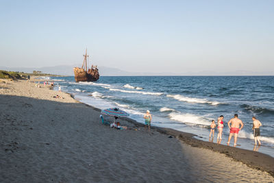 People on beach against clear sky