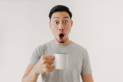 Portrait of man holding coffee cup against white background