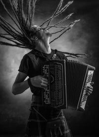Man playing accordion while tossing dreadlocks