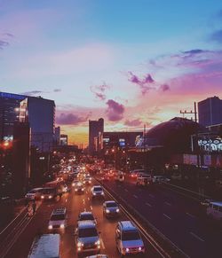 Traffic on road in city against sky during sunset