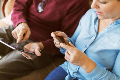 High angle view of senior man doing online shopping with daughter through credit card and digital tablet