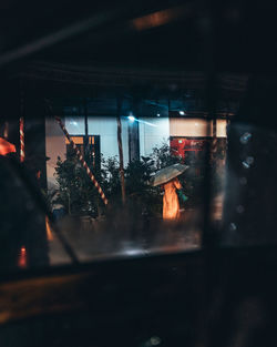 Illuminated building seen through wet glass window at night