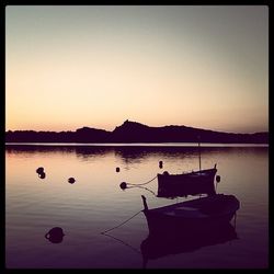 Boats in calm lake at sunset