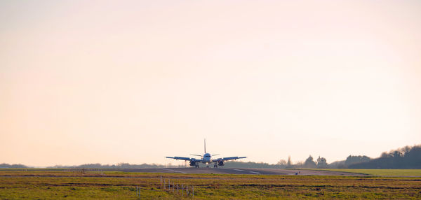 Airplane flying over field against sky