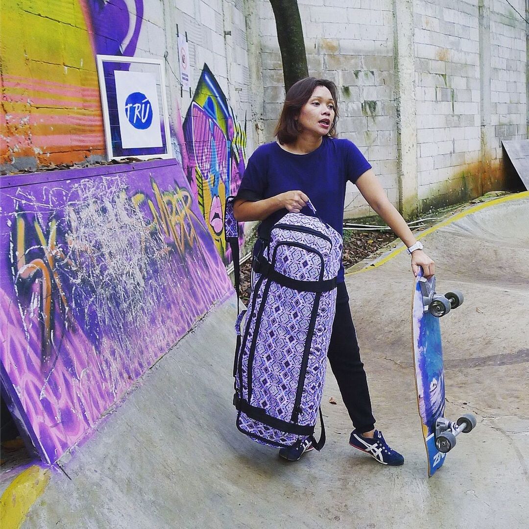 real people, one person, full length, lifestyles, front view, graffiti, young women, leisure activity, young adult, casual clothing, women, wall - building feature, architecture, built structure, portrait, day, standing, females, purple, beautiful woman