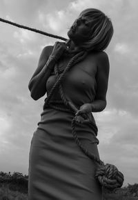 Low angle view of woman tied up with rope against sky