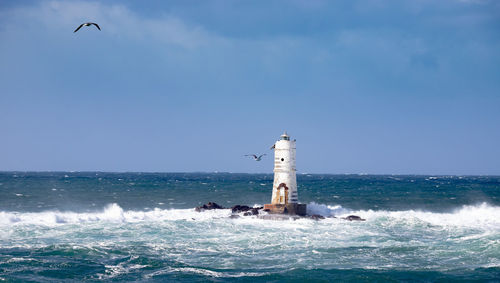 Lighthouse by sea against sky