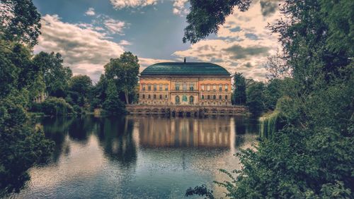Reflection of building in lake against cloudy sky