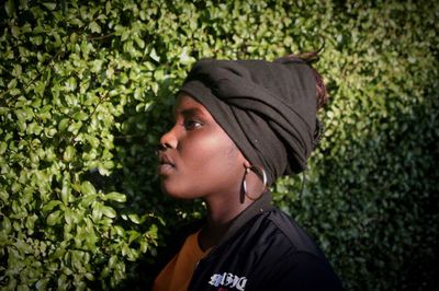 Side view of woman standing by hedge