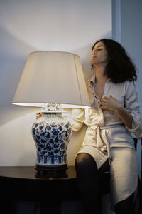 Mature woman by illuminated lamp at home