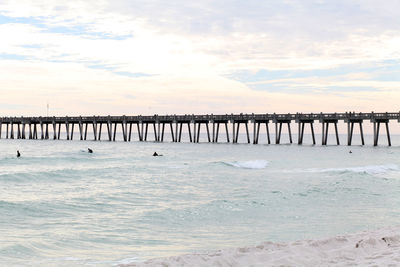 Pier on sea against cloudy sky