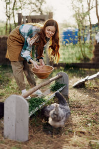 Happy female farmer feeding chickens at farm