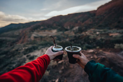 Midsection of man holding ice cream against mountains