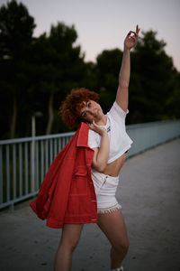 Midsection of woman with arms raised standing against trees