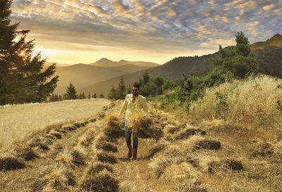 Man carrying crops while walking on agricultural field