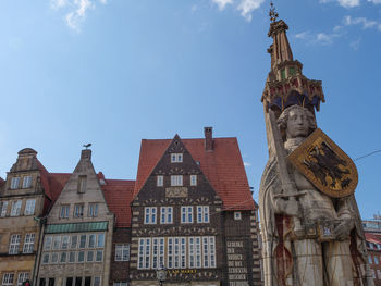 Low angle view of statue against building against sky