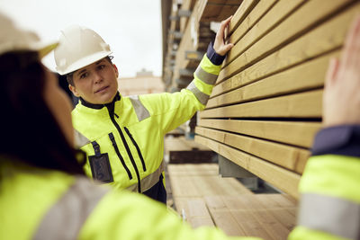 Multiracial female workers discussing over planks stacked at industry