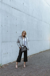 Portrait of young woman standing against wall