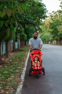 Portrait of man pushing stroller on the road.