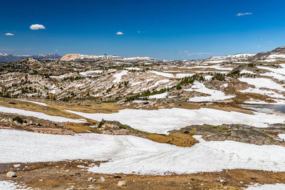 Snow covered landscape against blue sky