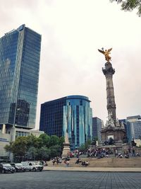 Statue in city against sky